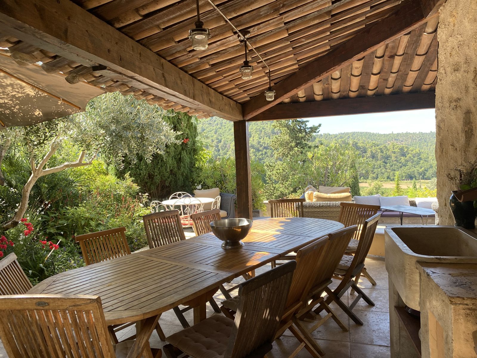 La terrasse couverte et sa grande table, face aux collines